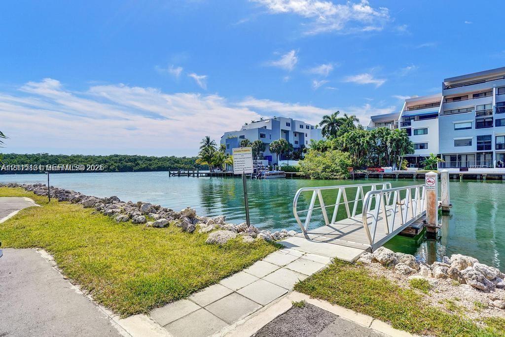 Waterfront property featuring a metal gangway, stone-lined bulkhead, paved pathway, and grass landscaping Waterfront property featuring a metal gangway, stone-lined bulkhead, paved pathway, and grass landscaping