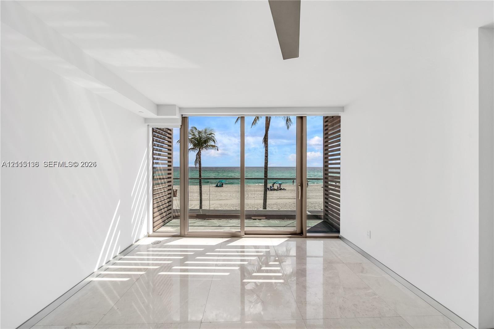 Floor-to-ceiling sliding glass doors, polished stone flooring, custom slatted wood screening, and a recessed ceiling fan