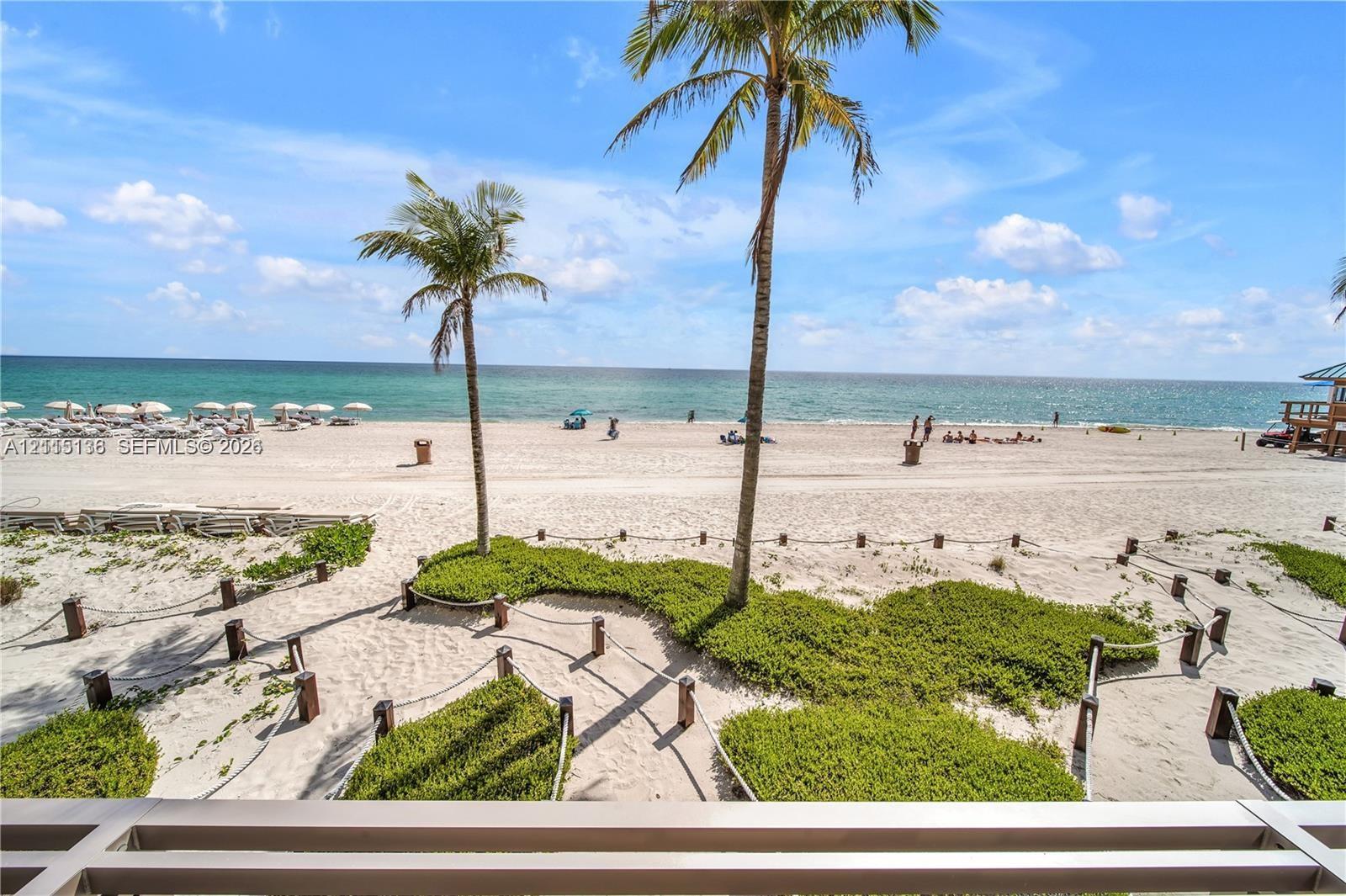 Direct oceanfront exposure featuring expansive sandy shoreline, established palm trees, rope-bordered landscaping, and horizontal railing Direct oceanfront exposure featuring expansive sandy shoreline, established palm trees, rope-bordered landscaping, and horizontal railing
