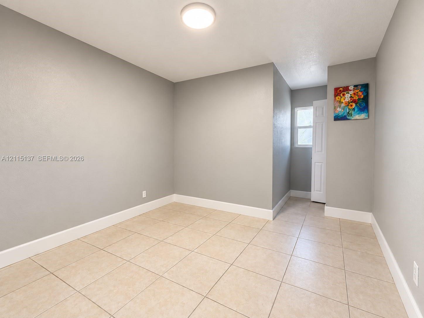 Neutral-toned wall finish, large-format neutral floor tiling, flush-mount ceiling lighting, and a multi-panel interior door Neutral-toned wall finish, large-format neutral floor tiling, flush-mount ceiling lighting, and a multi-panel interior door