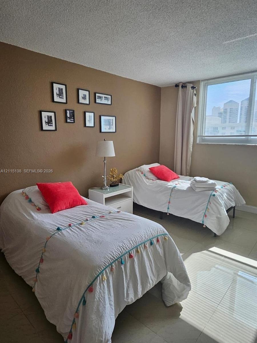 Room featuring neutral-toned walls, tile flooring, and a large window