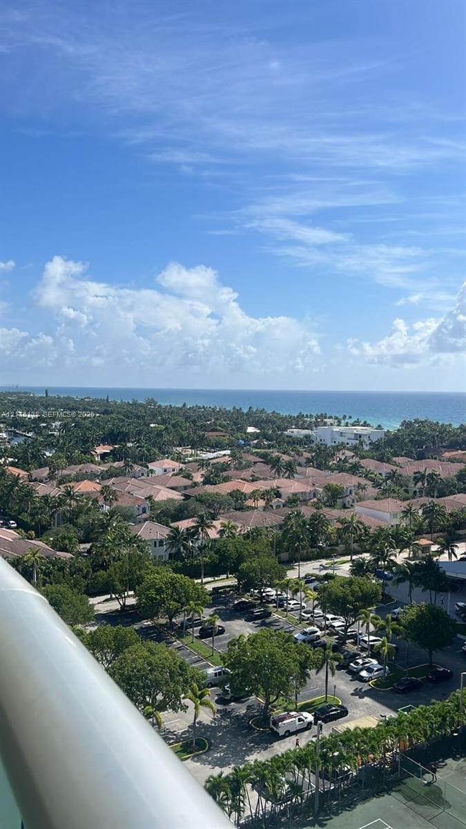 Elevated perspective featuring coastal horizon, mature tree canopy, and dedicated tennis court