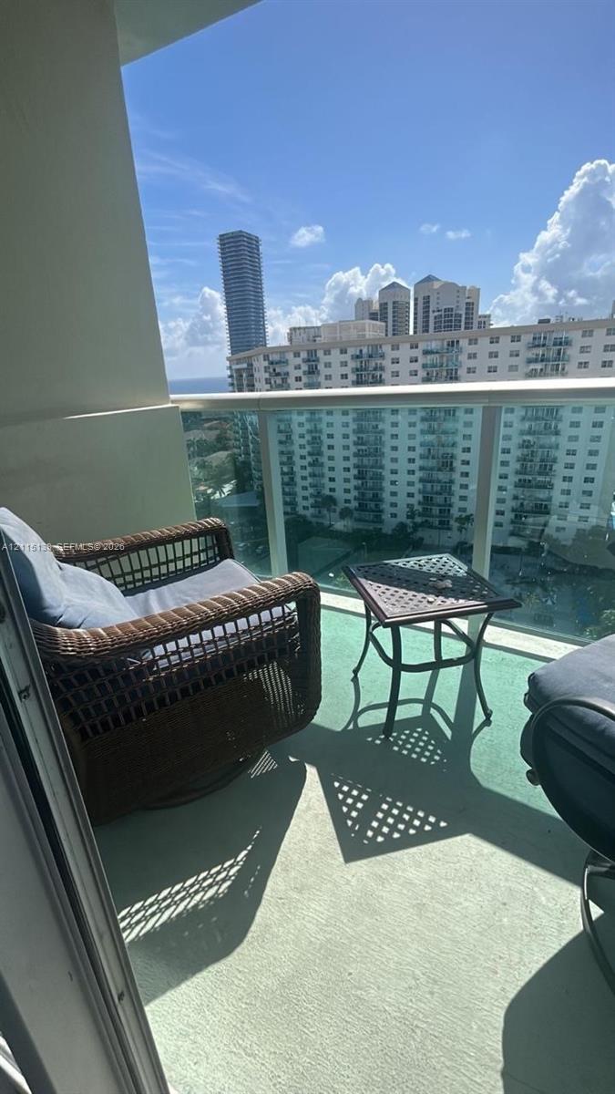 Covered balcony featuring a glass panel railing and solid surface flooring