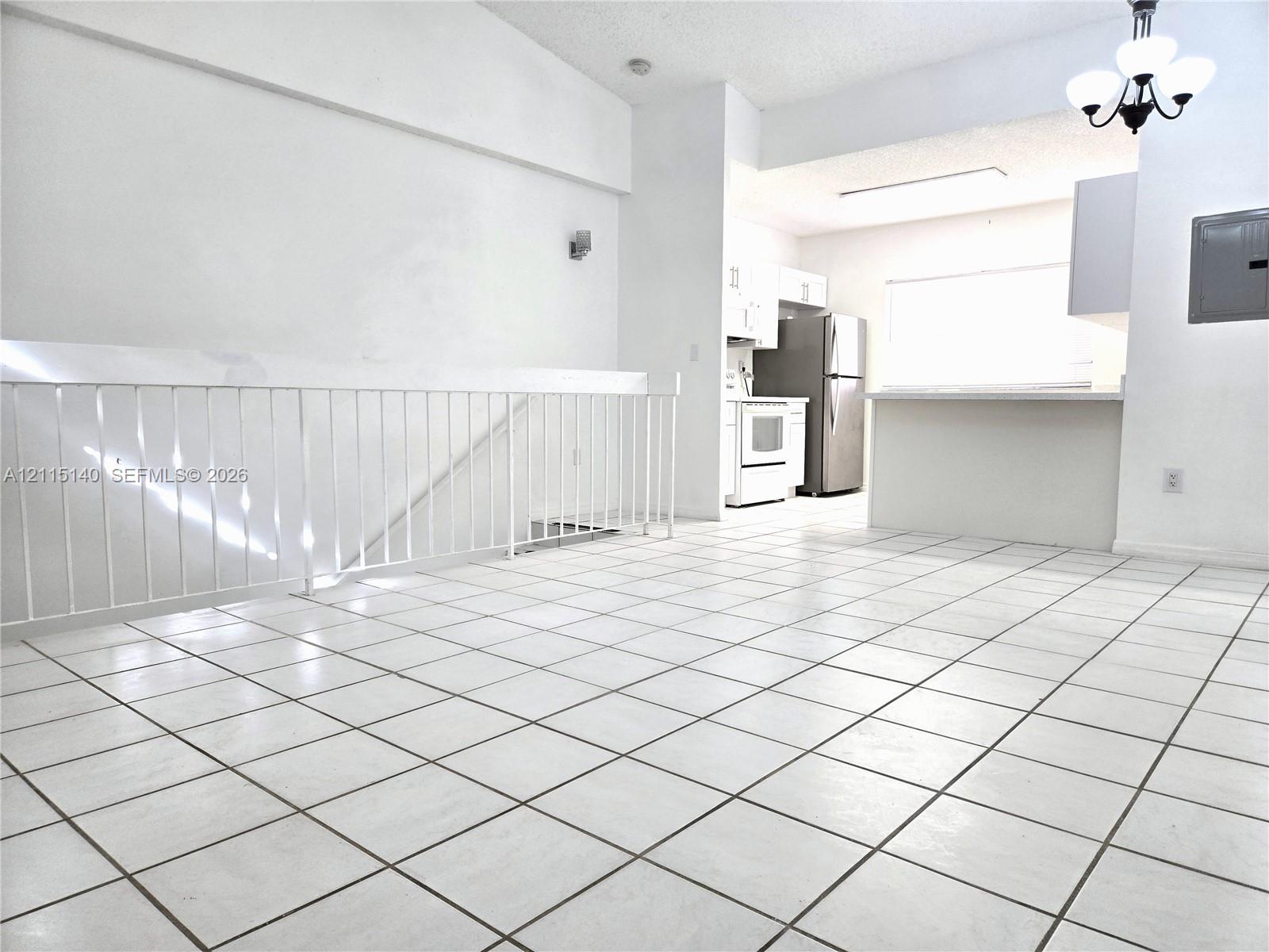 Tiled flooring, white cabinetry, integrated pass-through counter, and white metal railing