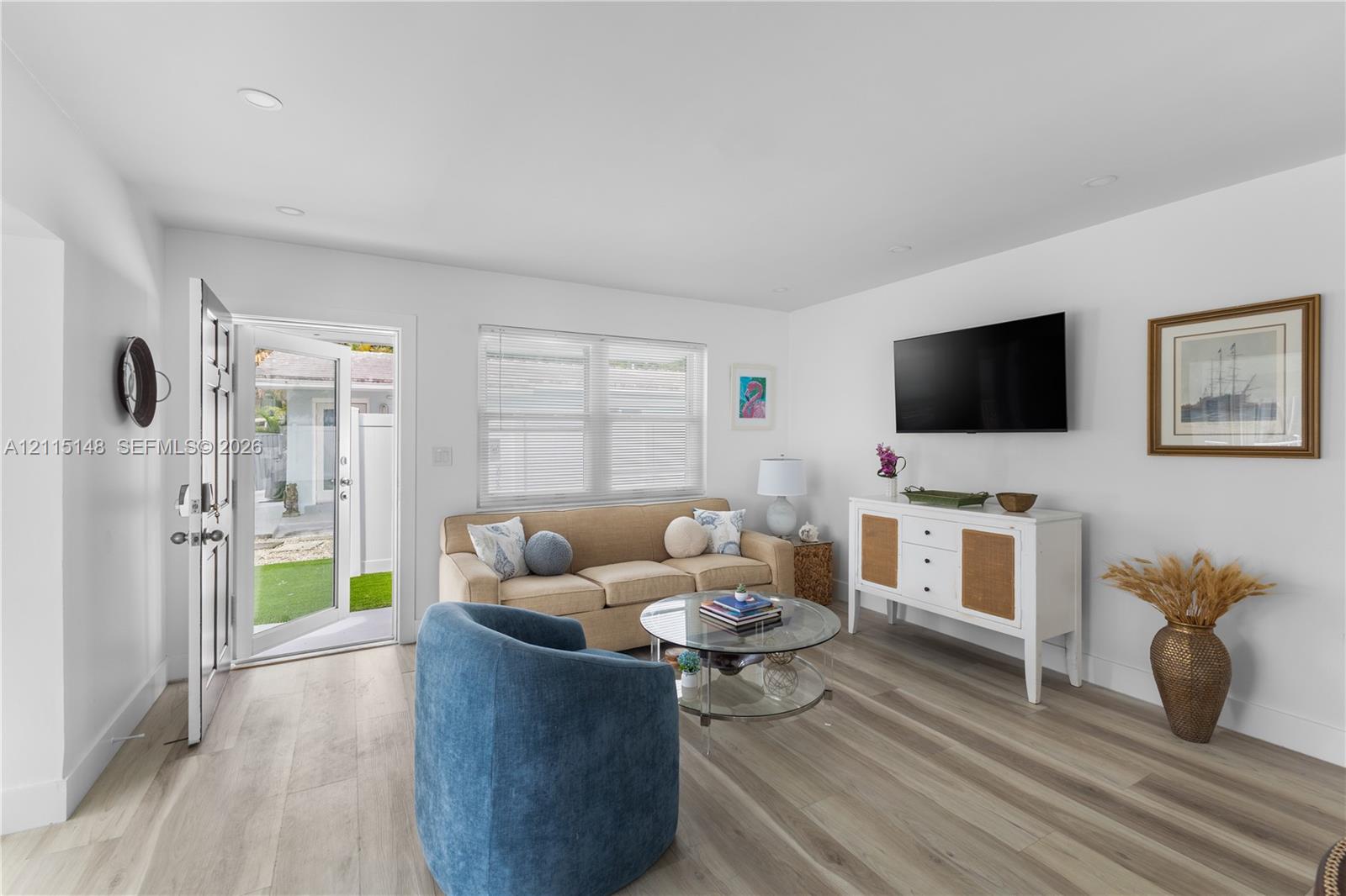 Open-concept interior featuring light-toned wood-finish flooring, recessed lighting, and a multi-pane entry door Open-concept interior featuring light-toned wood-finish flooring, recessed lighting, and a multi-pane entry door