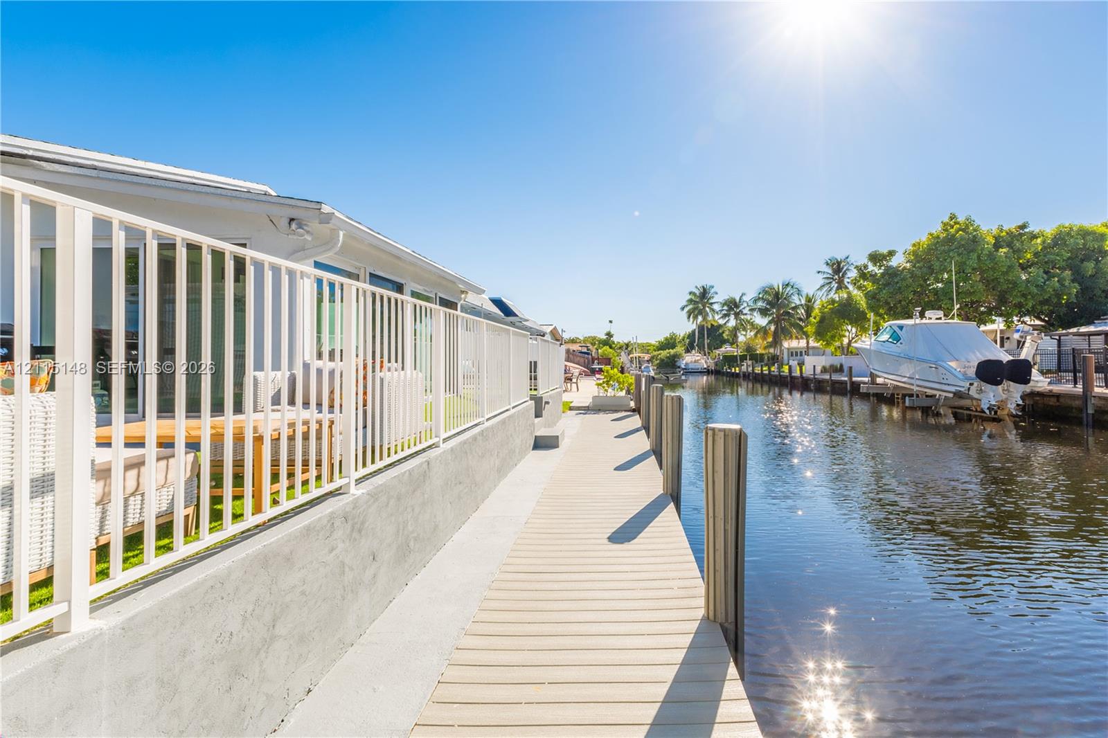 Waterfront property featuring a private concrete dock, nautical pilings, and a metal perimeter railing