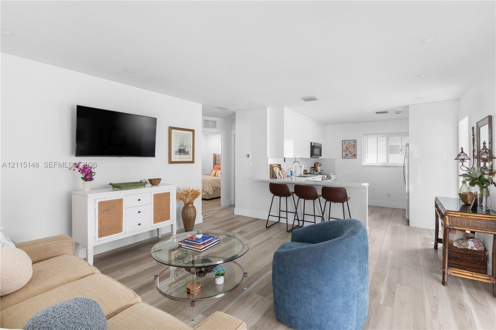 Open-concept living space featuring wood-finish flooring, recessed lighting, and a kitchen peninsula with a breakfast bar Open-concept living space featuring wood-finish flooring, recessed lighting, and a kitchen peninsula with a breakfast bar