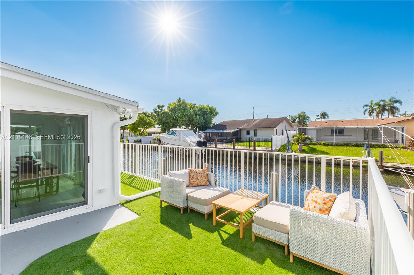 Waterfront patio featuring synthetic turf surfacing, white powder-coated railing, and direct water access Waterfront patio featuring synthetic turf surfacing, white powder-coated railing, and direct water access