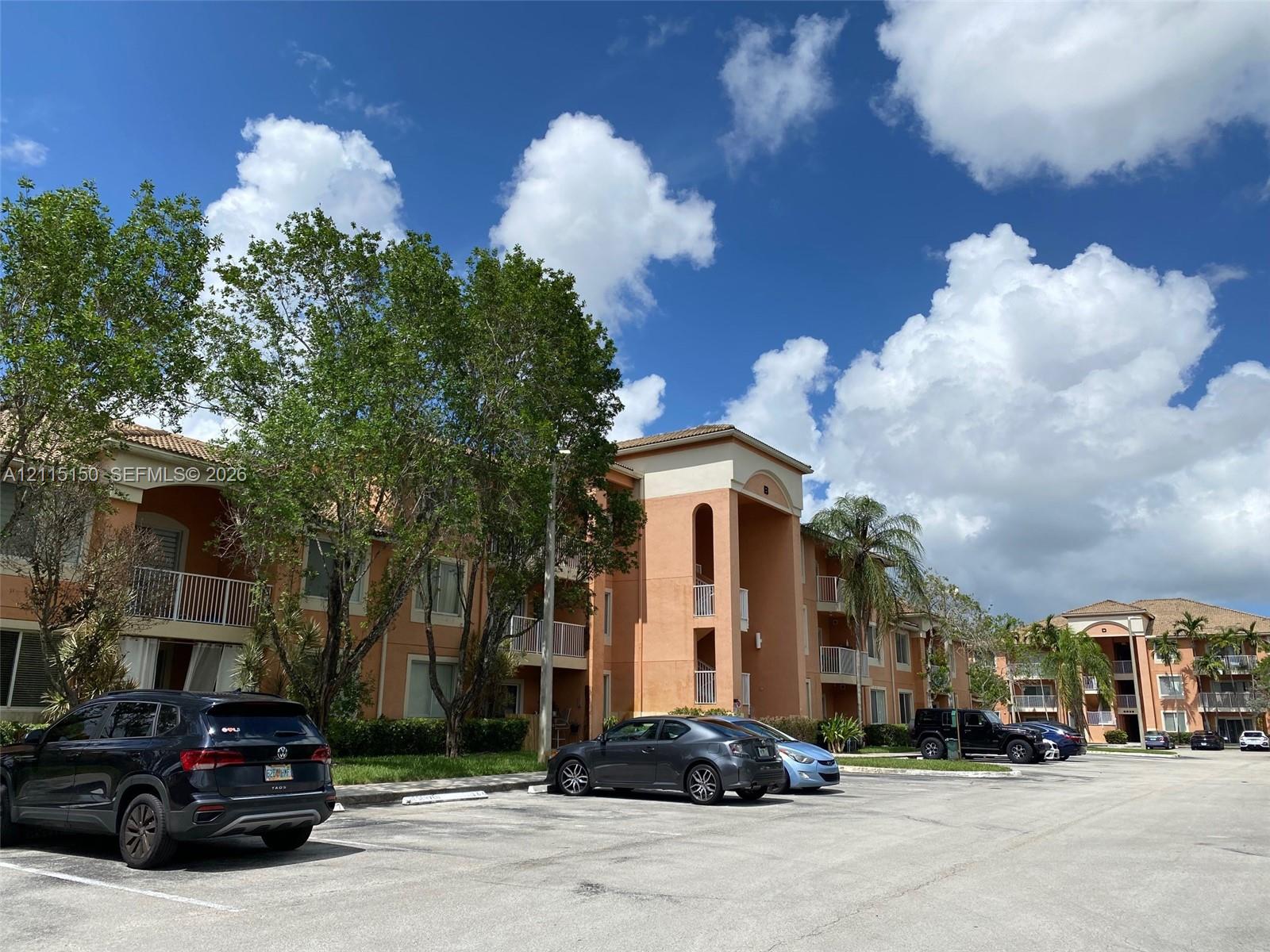 Multi-story stucco exterior featuring arched architectural detailing, private balconies with metal railings, and a tile roof