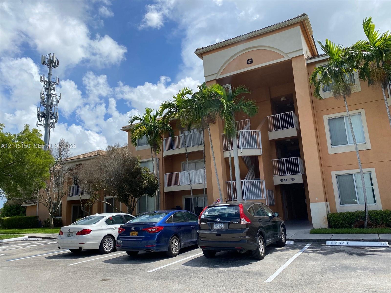 Multi-story stucco exterior featuring arched architectural detailing, private balconies with metal railings, and mature palm landscaping