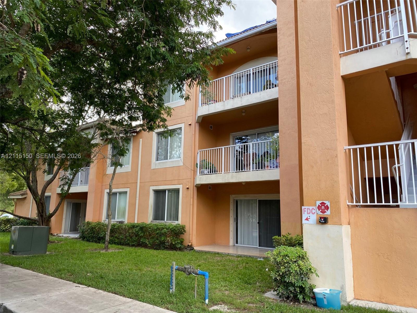 Multi-level exterior featuring stucco siding, white metal railings, sliding glass balcony doors, and ground-level patios