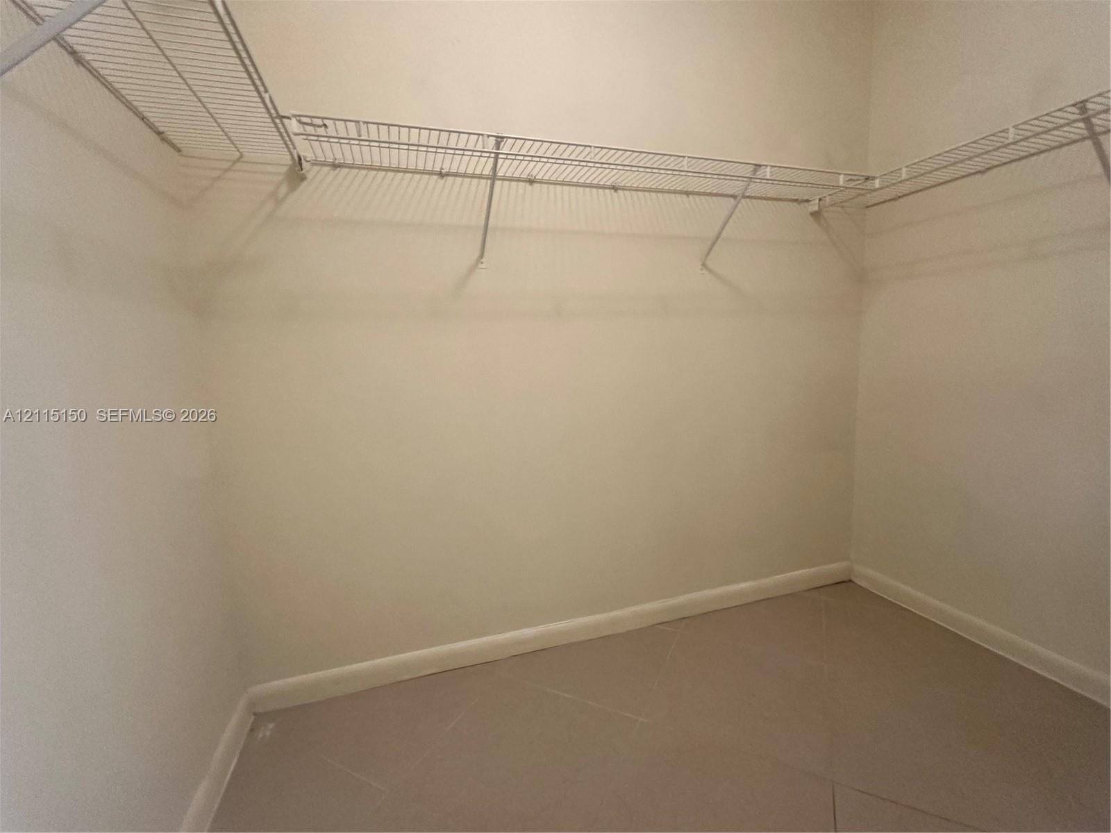 Walk-in storage space featuring neutral tile flooring and multi-level white wire shelving
