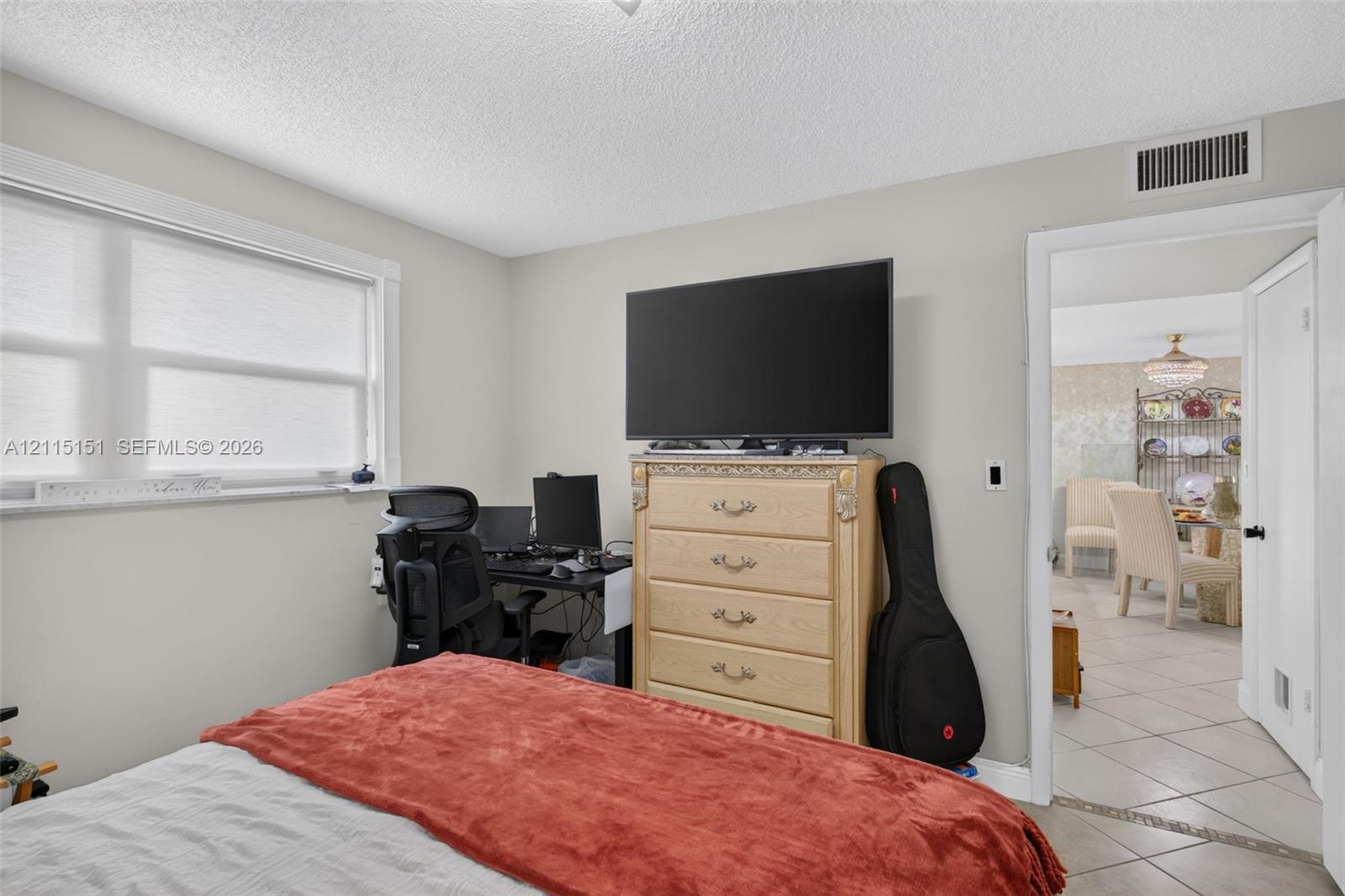 Neutral-toned bedroom featuring a large window with white frame and a solid-core interior door