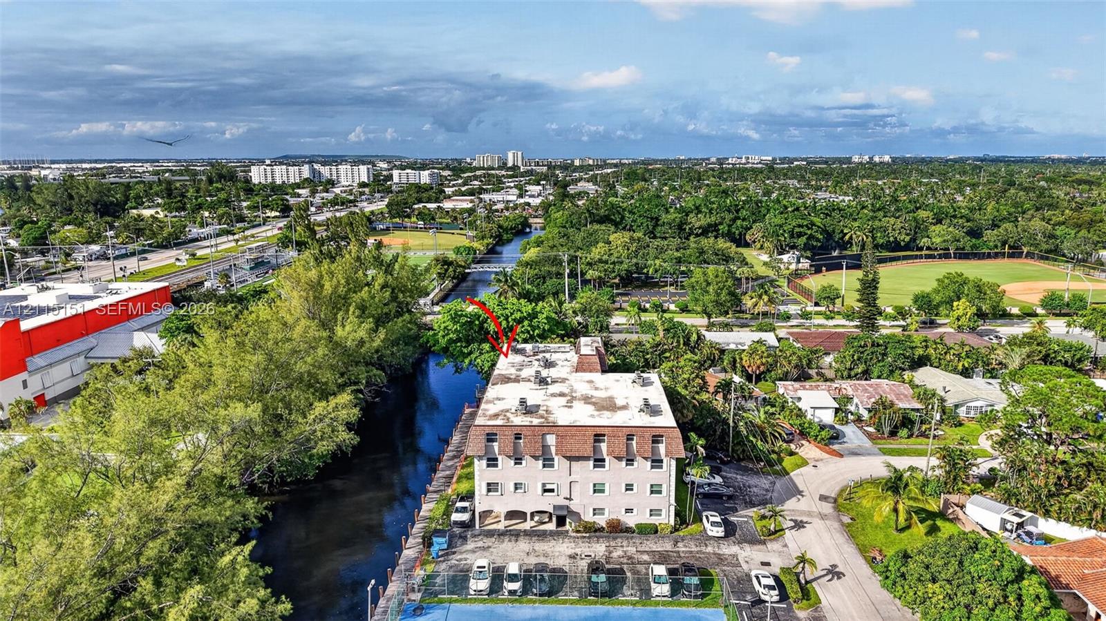 Multi-story building featuring a mansard roof, stucco exterior, paved surface parking, and a canal-side location