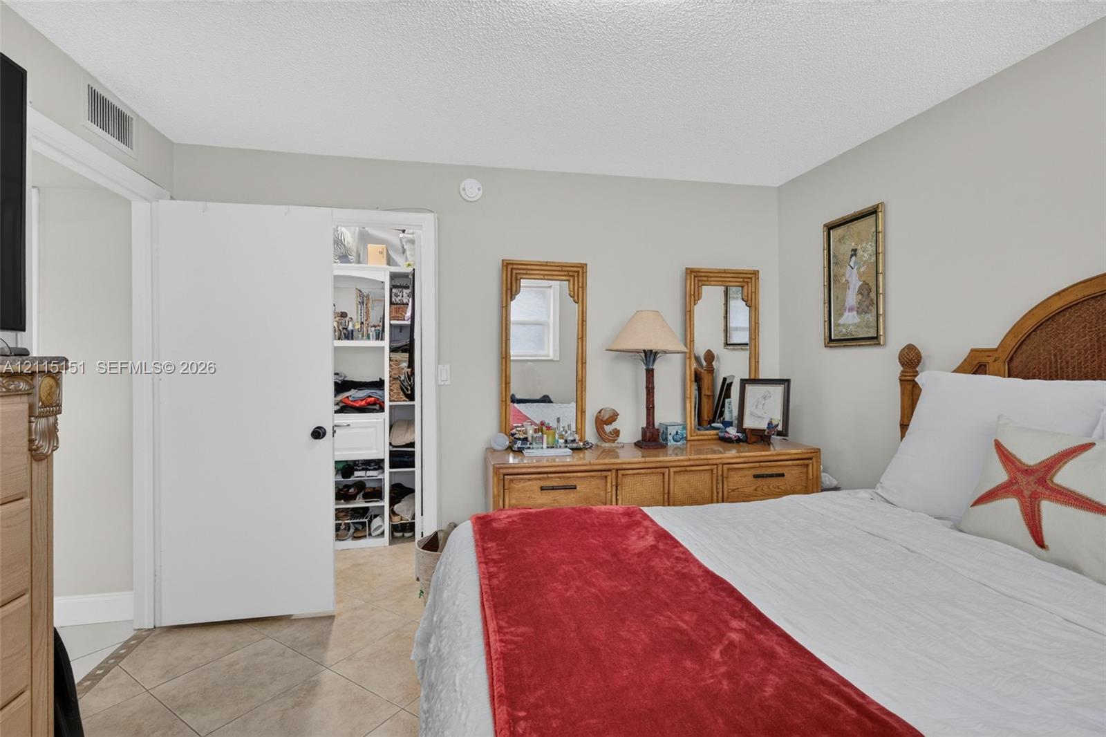 Bedroom featuring light-toned neutral wall paint, tile flooring laid on a diagonal pattern, and a built-in closet with integrated shelving