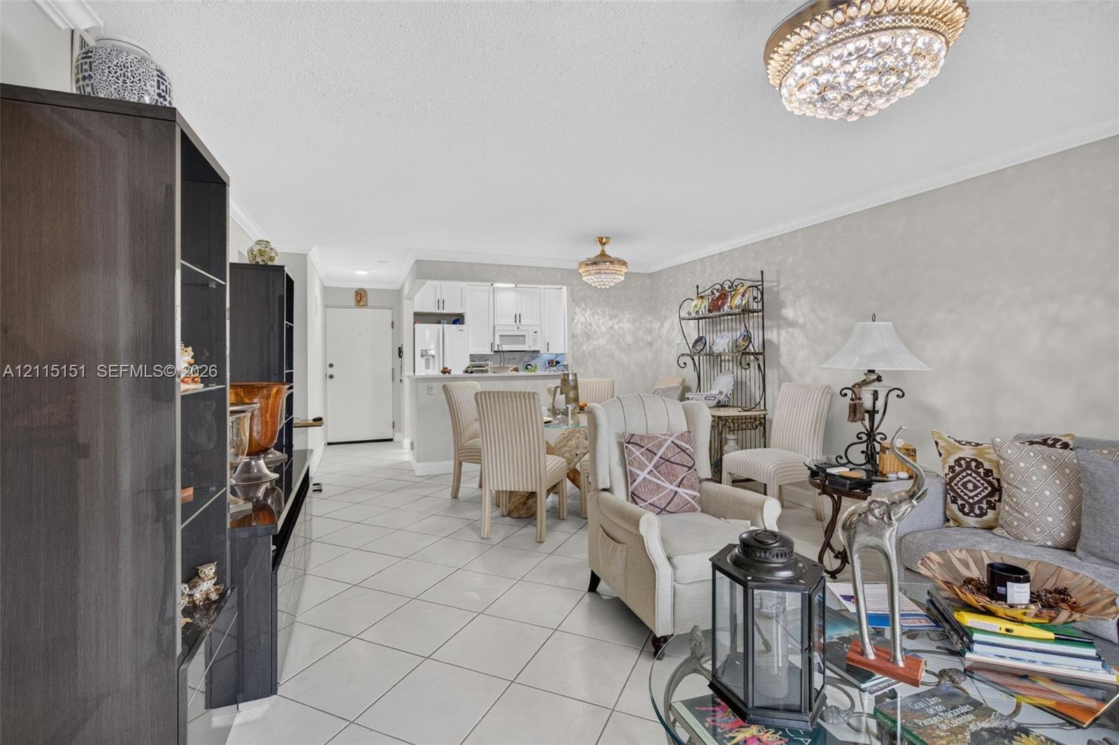 Open-concept interior featuring light-colored tile flooring, decorative crystal flush-mount lighting, and neutral wall tones