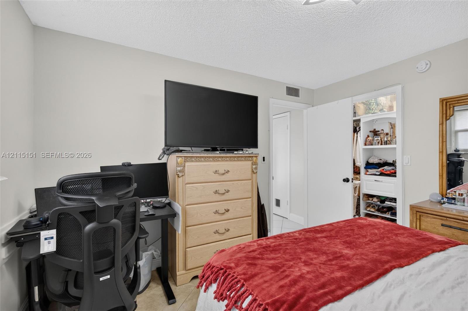 Built-in reach-in closet featuring white shaker-style cabinetry, open shelving, and a glass-paneled upper storage section