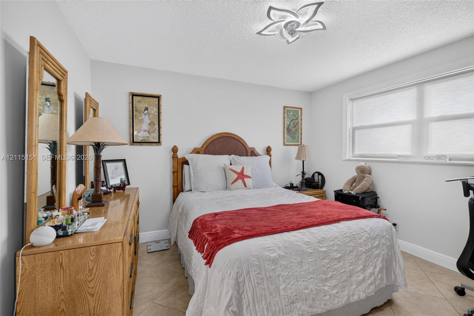 Room featuring neutral wall paint, large format tile flooring, and a decorative floral-shaped ceiling fixture