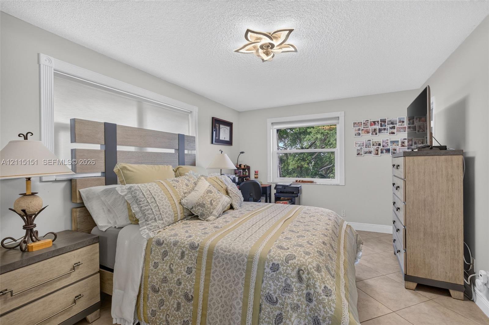 Neutral-toned interior featuring ceramic tile flooring, two windows with white casings, and a multi-petal style flush-mount ceiling light