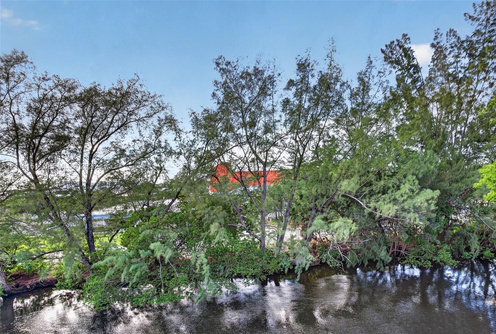 Waterfront property featuring mature trees and established landscape