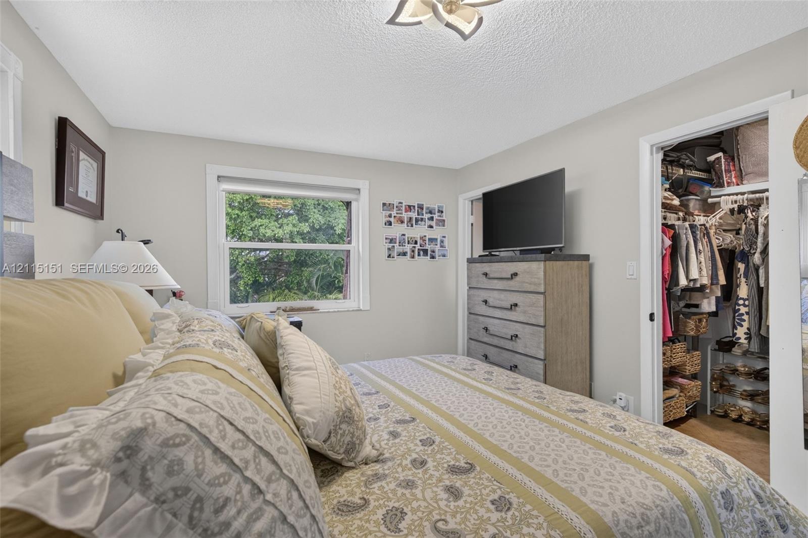 Neutral interior room featuring a single-hung window, white wall finish, and a ceiling-mounted light fixture with petal-inspired details