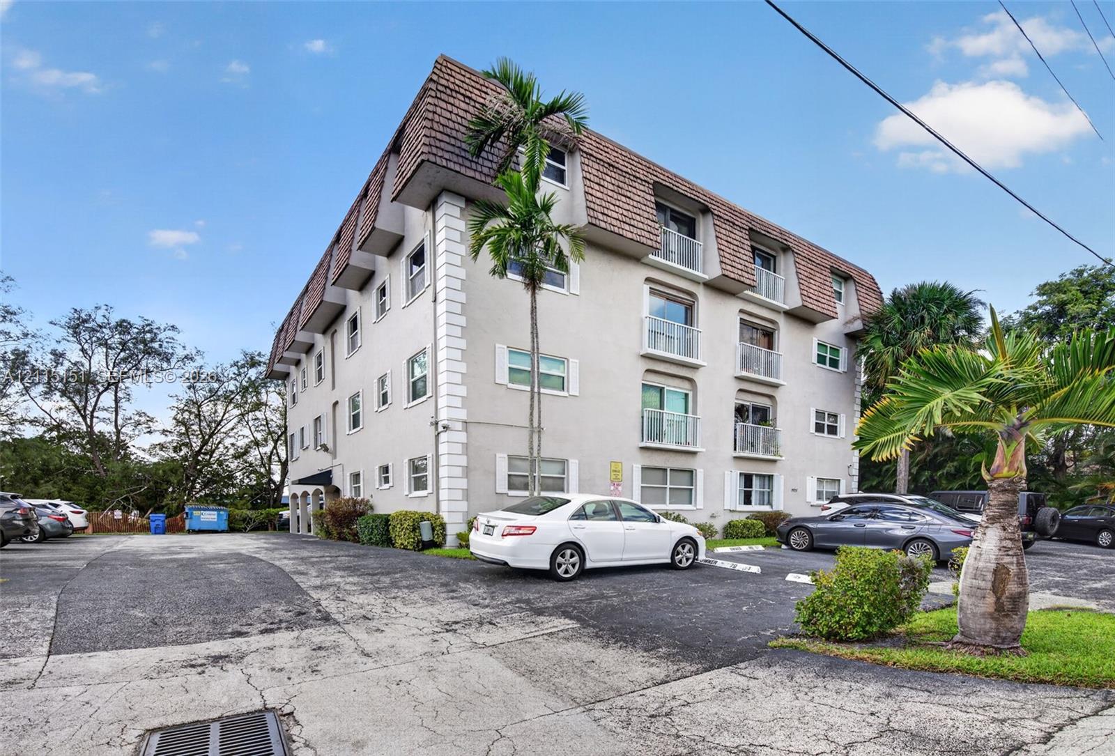 Multi-story building exterior featuring a mansard roofline, stucco facade with corner quoins, and multiple private balconies with metal railings Multi-story building exterior featuring a mansard roofline, stucco facade with corner quoins, and multiple private balconies with metal railings