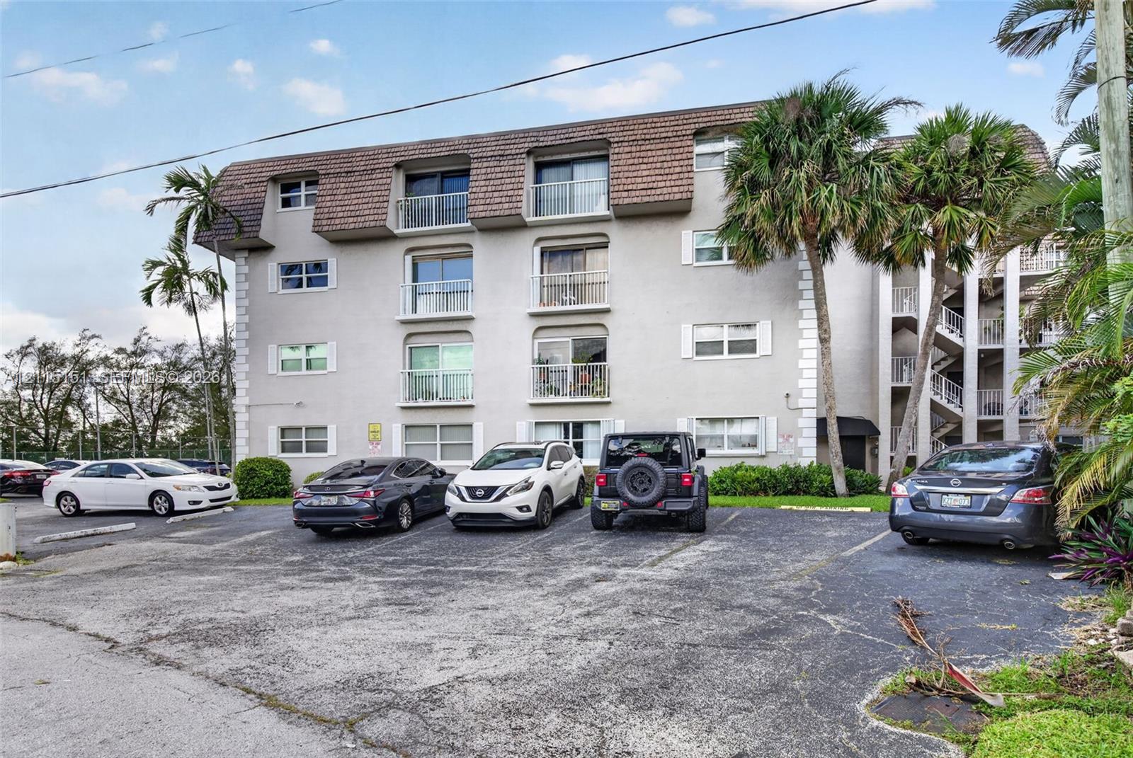 Multi-story exterior featuring a textured facade, mansard-style roofline, and private balconies with metal railings Multi-story exterior featuring a textured facade, mansard-style roofline, and private balconies with metal railings