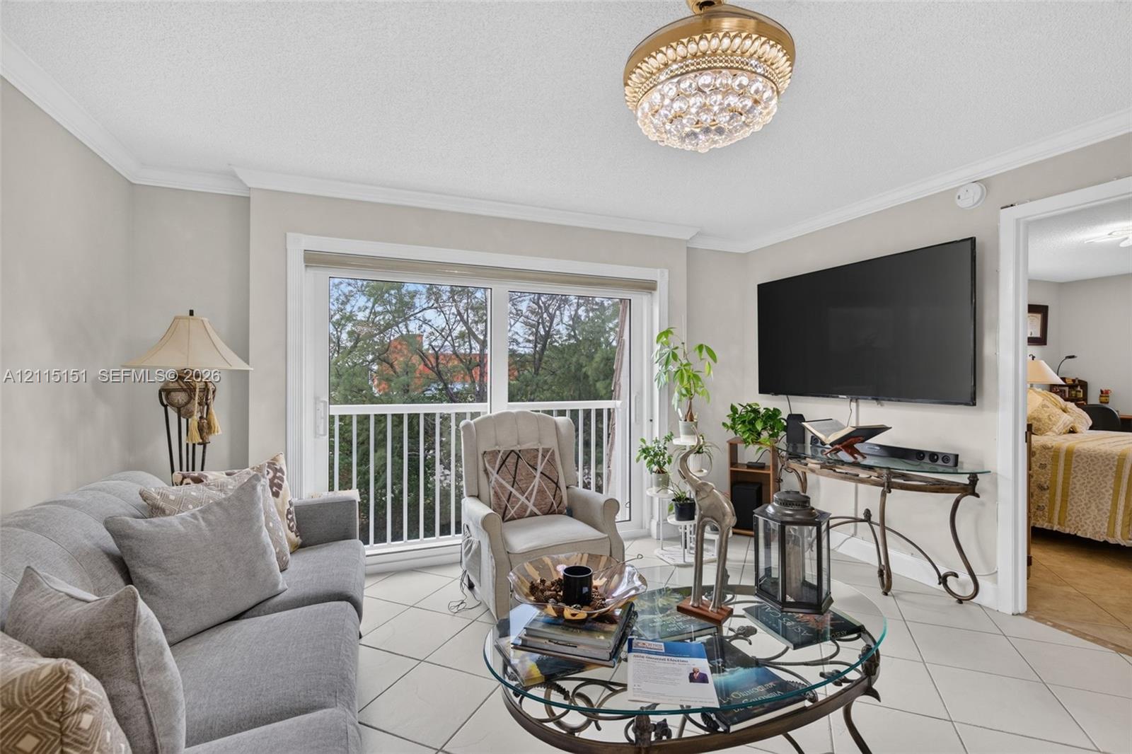 Ceramic tile flooring, crown molding, decorative crystal chandelier, and glass sliding door providing access to a private balcony