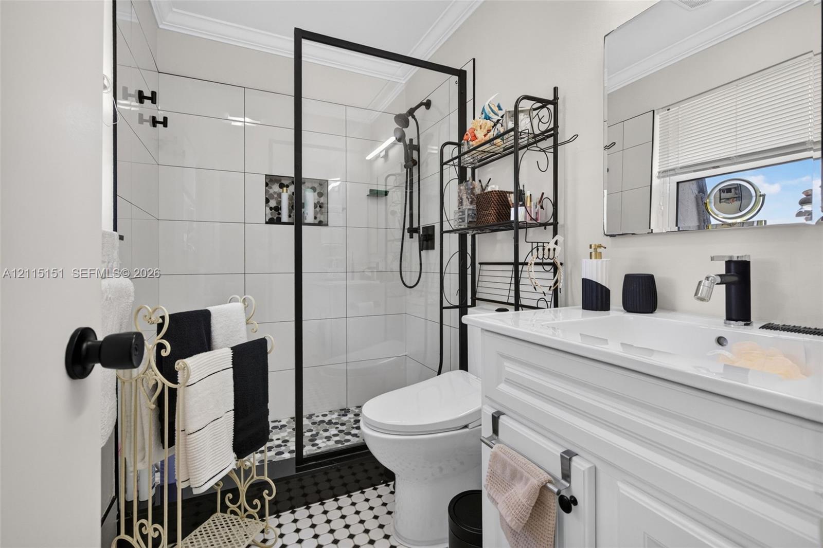 Full bathroom featuring a glass-enclosed shower with matte black fixtures, white subway wall tile, a built-in recessed niche, and a patterned tile floor