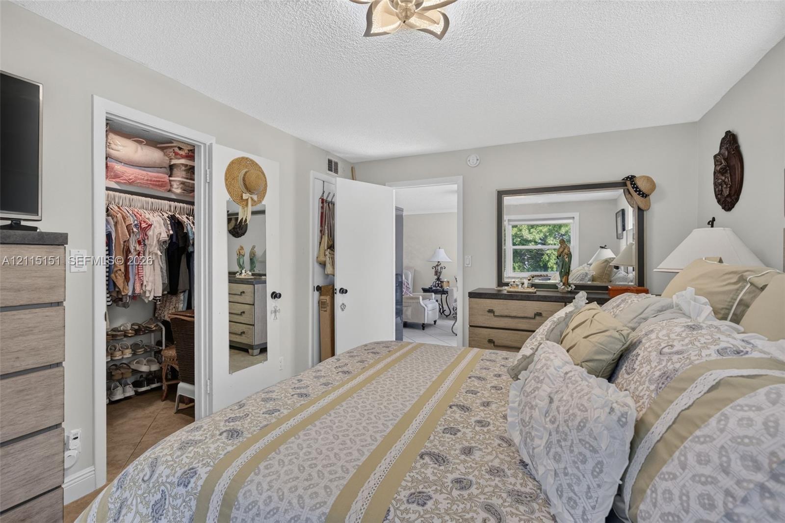 Bedroom featuring a multi-pane window, closet with a mirrored door, interior doorway, and a ceiling-mounted light fixture