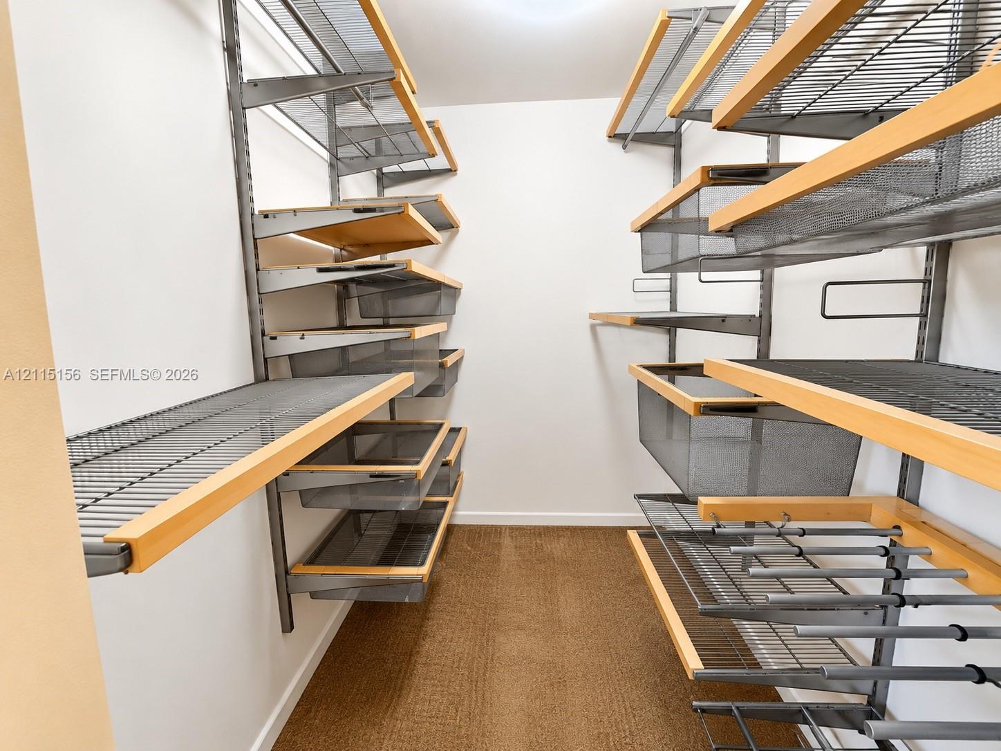 Custom storage system featuring metal shelving units, integrated wood-trim shelving, slide-out wire baskets, and hanging rods Custom storage system featuring metal shelving units, integrated wood-trim shelving, slide-out wire baskets, and hanging rods