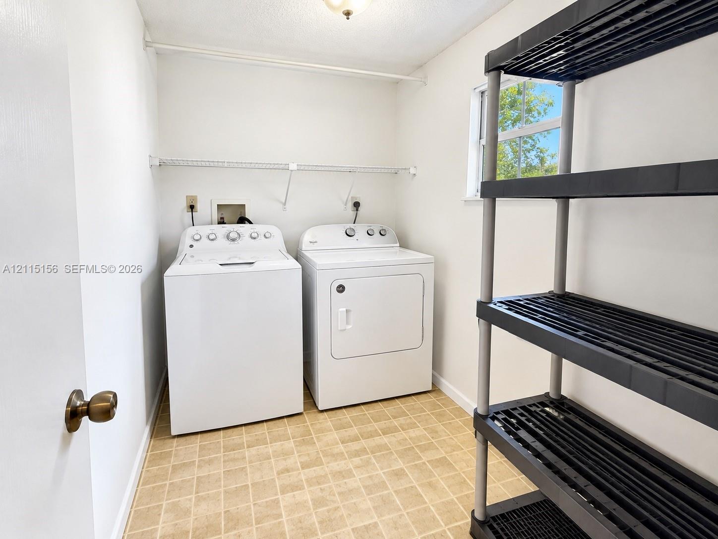 Laundry room featuring vinyl tile flooring, a window providing natural light, and an installed wire shelving unit
