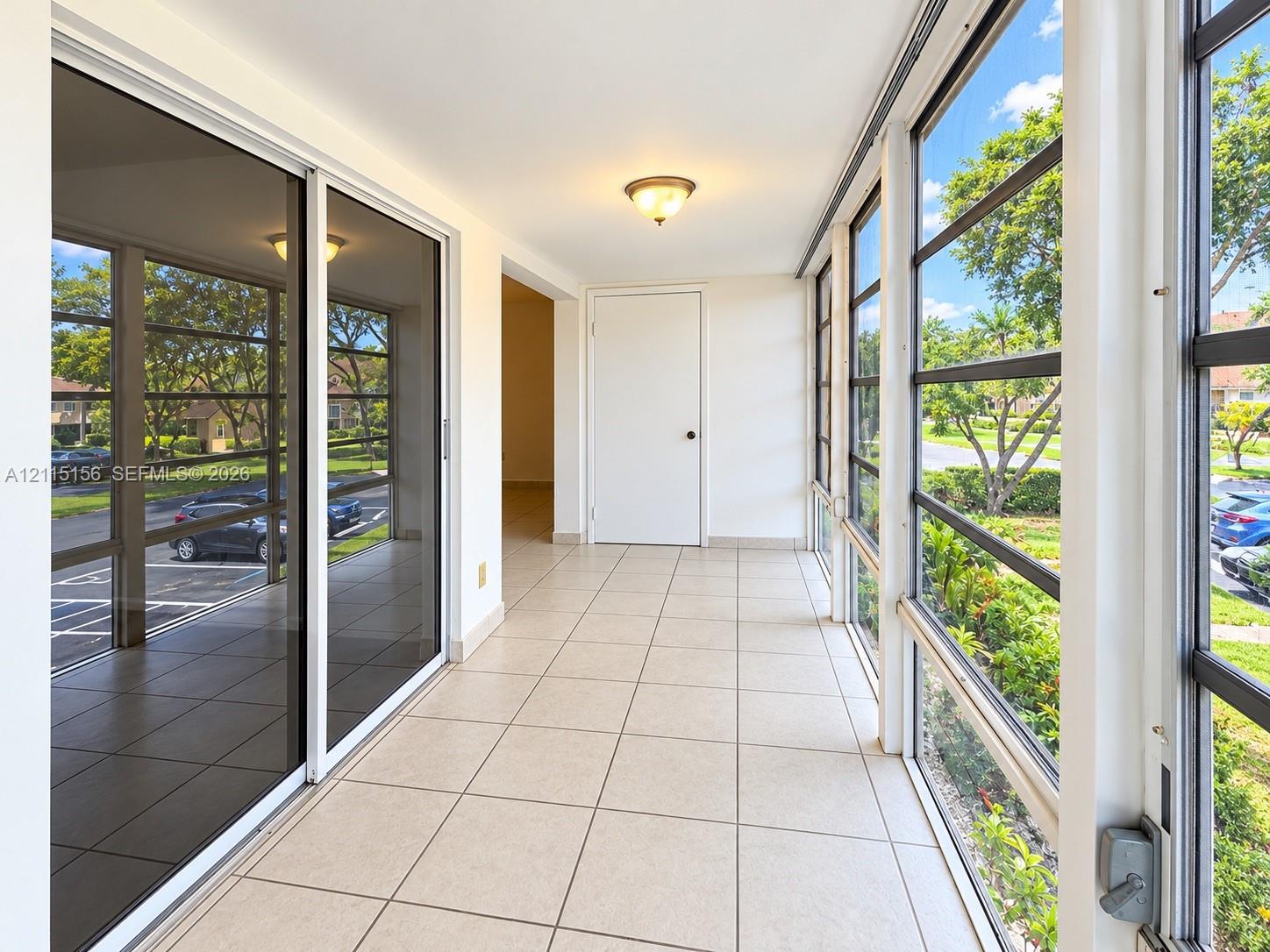 Enclosed patio featuring floor-to-ceiling screened windows, large-format tile flooring, sliding glass door entry, and flush-mount lighting Enclosed patio featuring floor-to-ceiling screened windows, large-format tile flooring, sliding glass door entry, and flush-mount lighting
