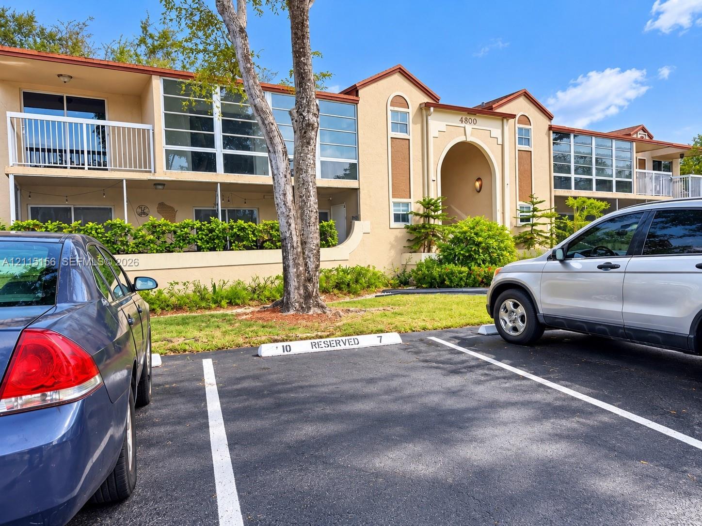 Stucco exterior featuring second-level private balconies with railings, multi-pane window configurations, and a prominent arched entryway