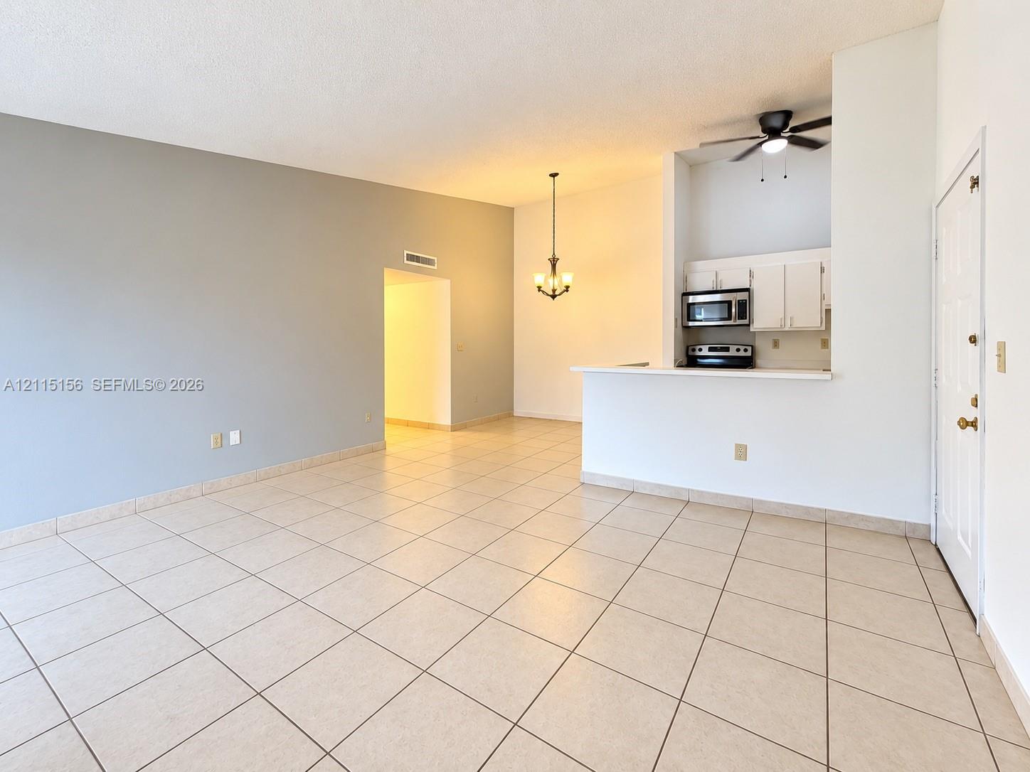 Open-concept interior featuring large-format tile flooring, vaulted ceilings, breakfast bar, built-in cabinetry, and integrated lighting fixtures