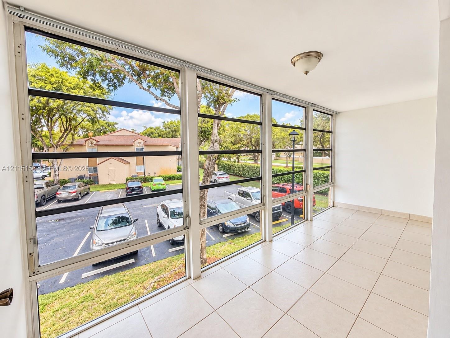 Enclosed balcony featuring light-toned tile flooring, floor-to-ceiling windows, and a flush-mount ceiling light fixture Enclosed balcony featuring light-toned tile flooring, floor-to-ceiling windows, and a flush-mount ceiling light fixture