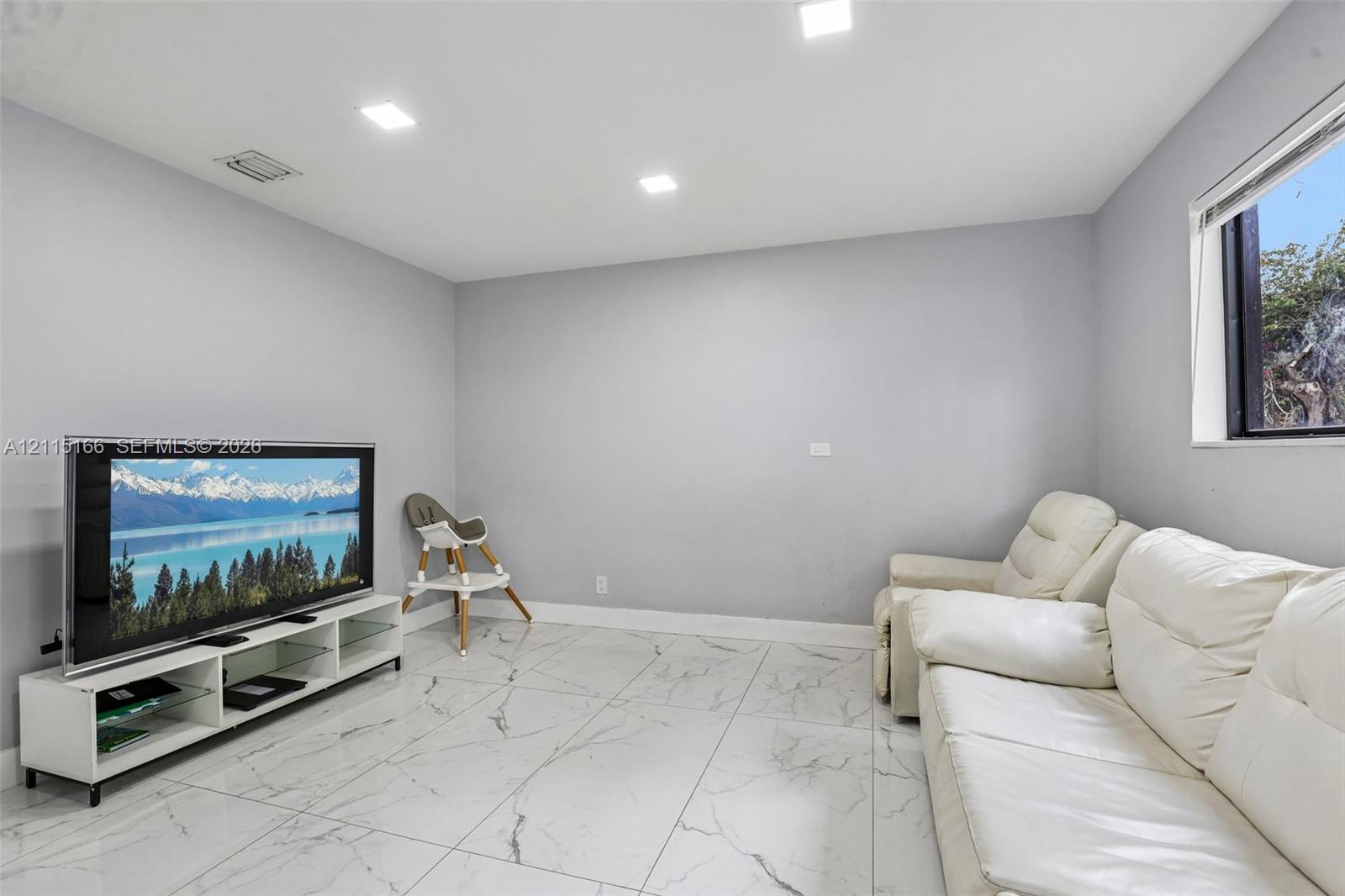 Room featuring large-format porcelain tile flooring with veining, recessed LED lighting, and a window with a white frame