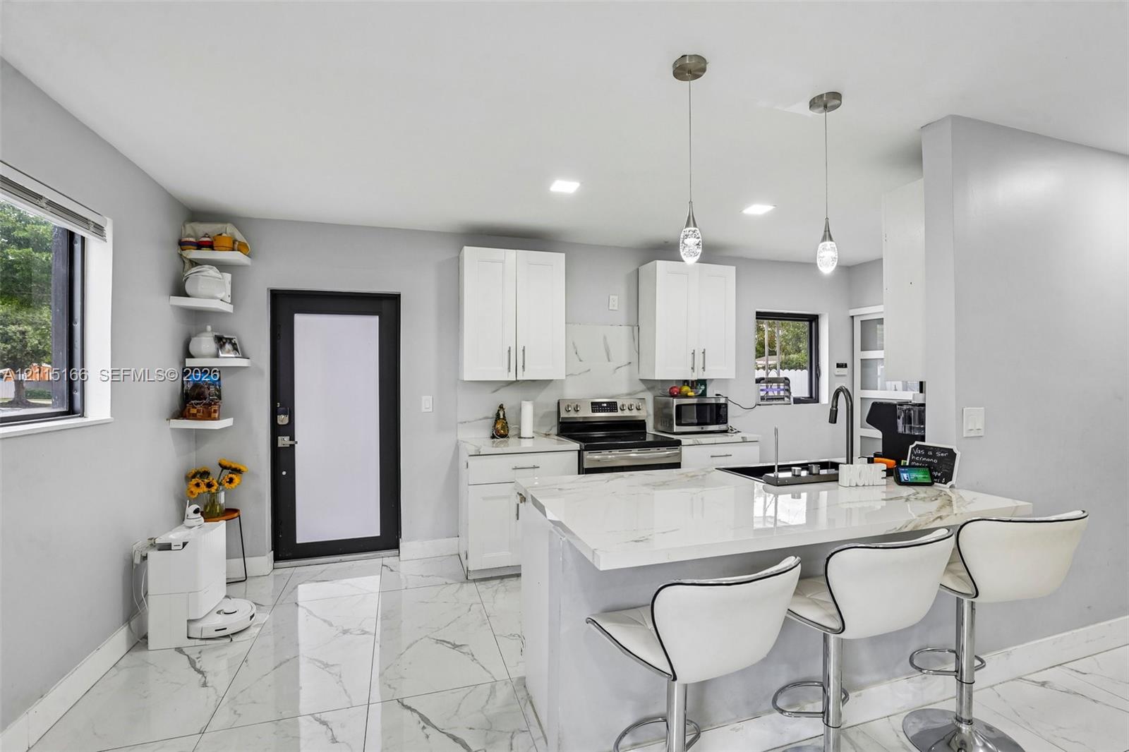 Kitchen featuring white cabinetry, stone-finish countertops, tile flooring, built-in shelving, and dual pendant lighting
