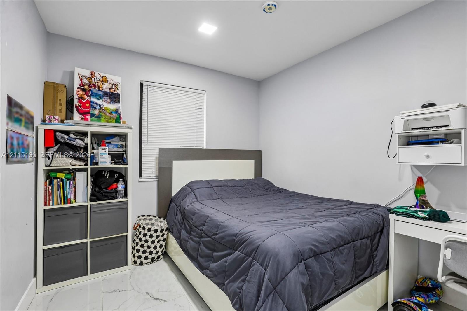 Neutral interior room featuring white stone-finish tile flooring, recessed ceiling lighting, and a window with horizontal blinds