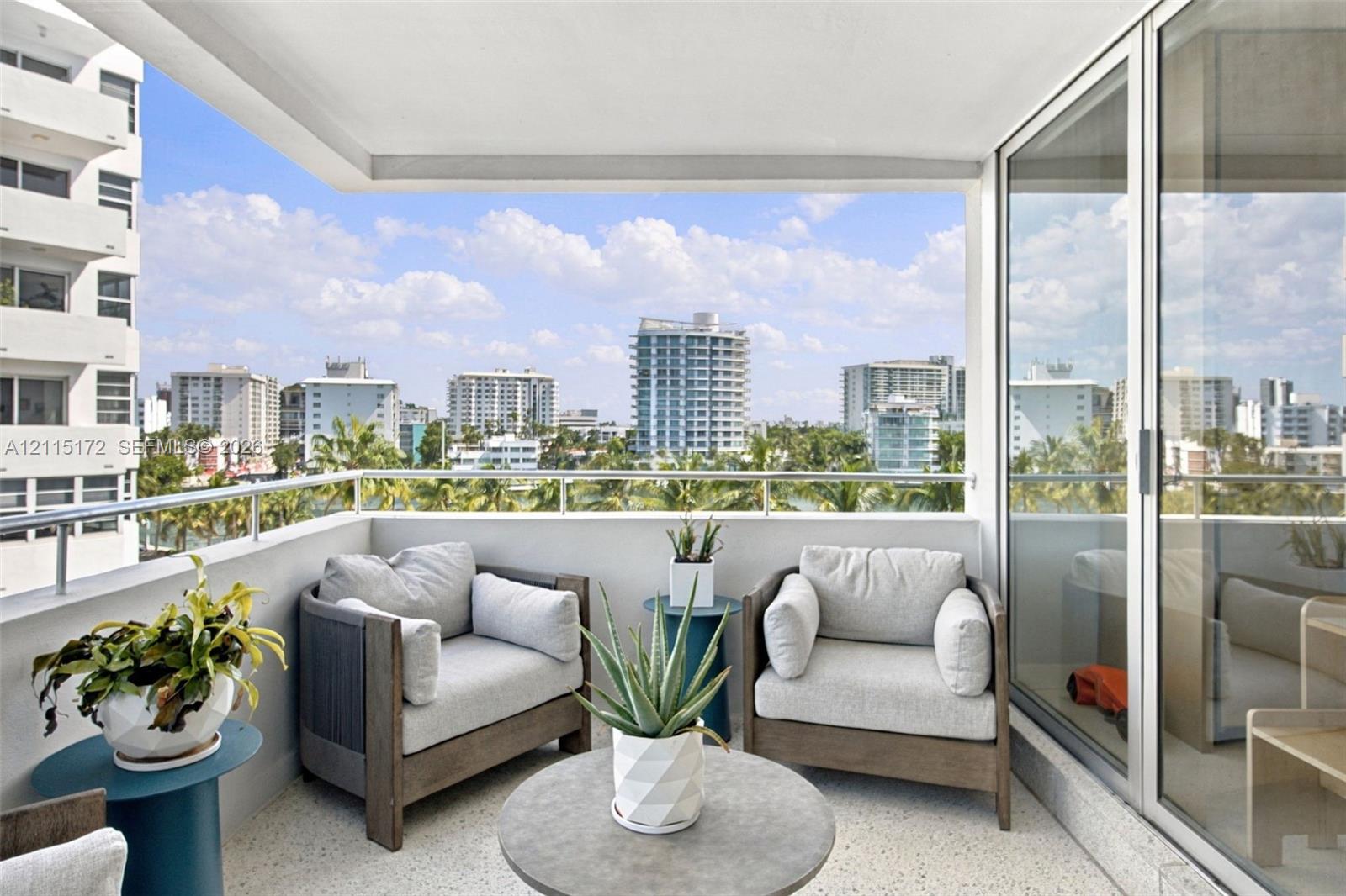 Covered balcony featuring a metal railing and terrazzo flooring, offering an expansive outlook of the surrounding cityscape