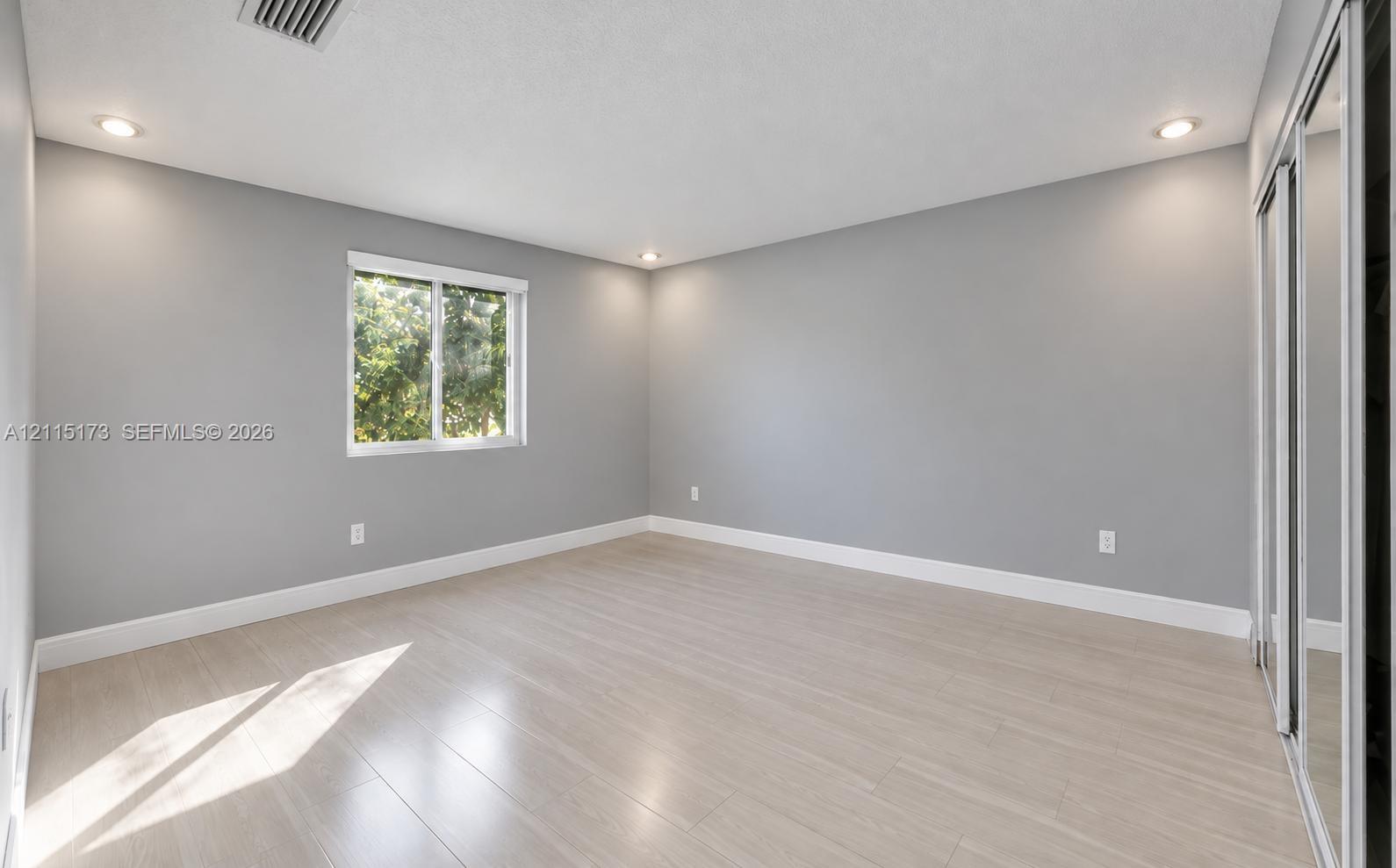 Neutral interior featuring wood-finish flooring, recessed lighting, and a sliding mirrored closet door