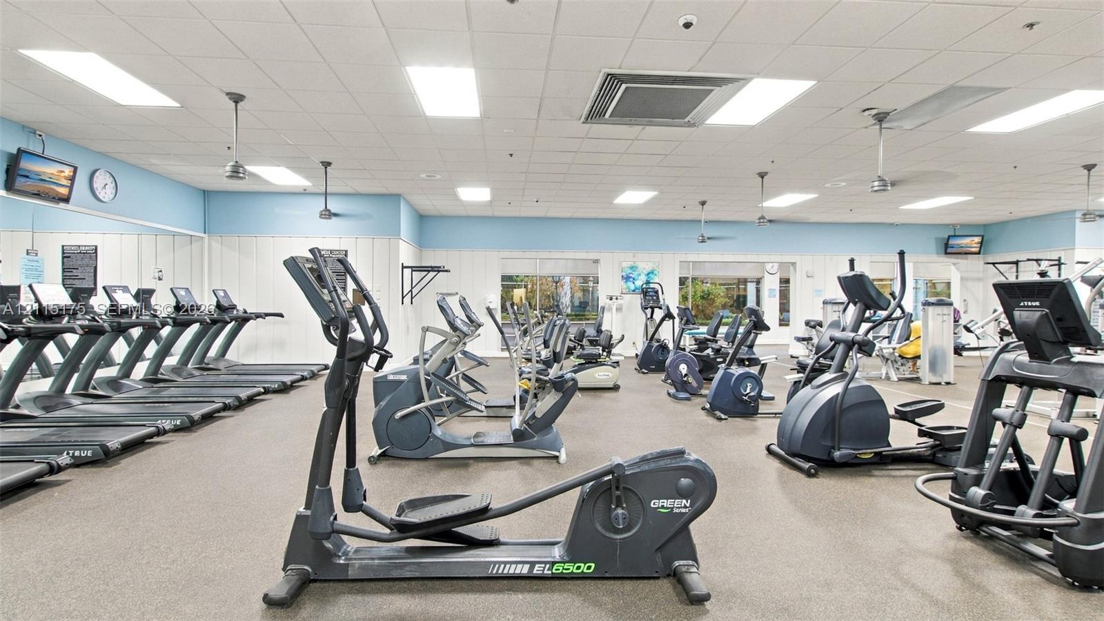 Fitness center featuring commercial-grade exercise equipment, mirrored wall panels, drop ceiling with recessed lighting, and resilient athletic flooring