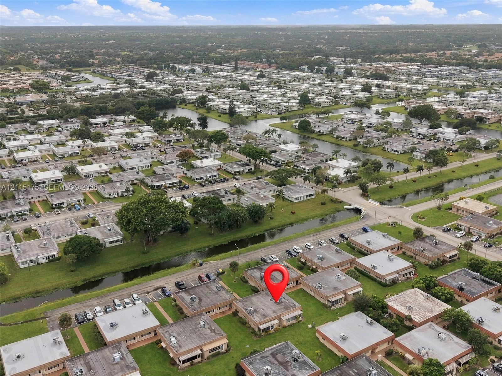 Aerial perspective of the villa situated within a community featuring green spaces and canal water features