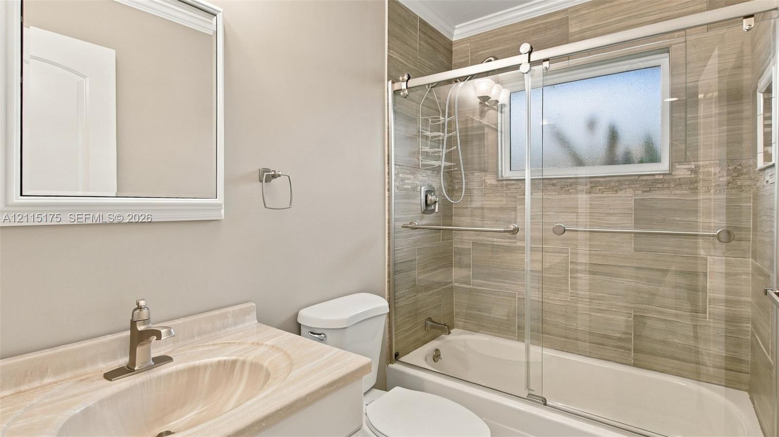 Guest bathroom featuring a tiled shower-tub combination enclosed by sliding glass doors
