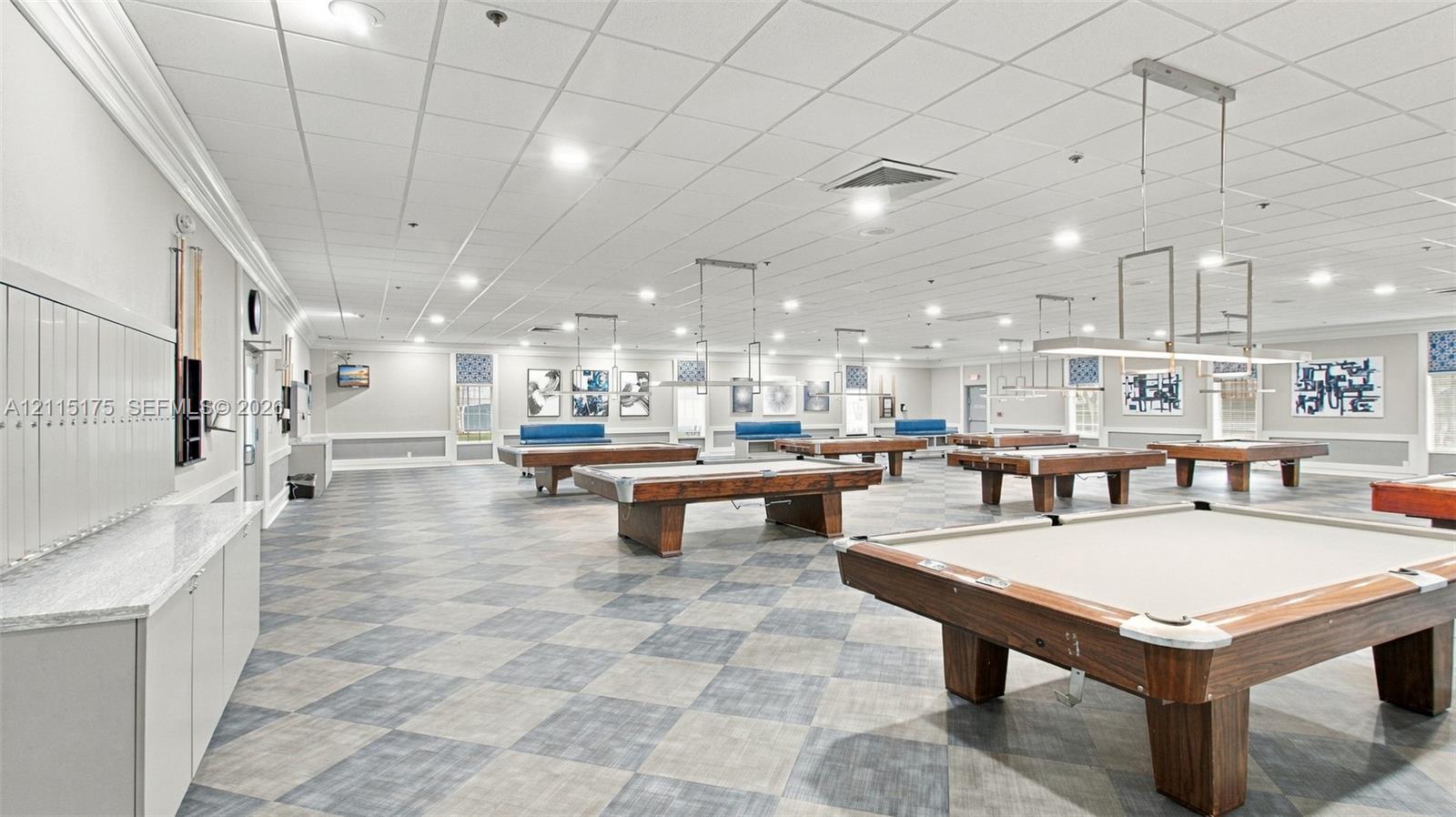 Billiards room featuring checkered flooring, recessed ceiling lighting, built-in cabinetry with stone-finish countertops, and linear pendant light fixtures