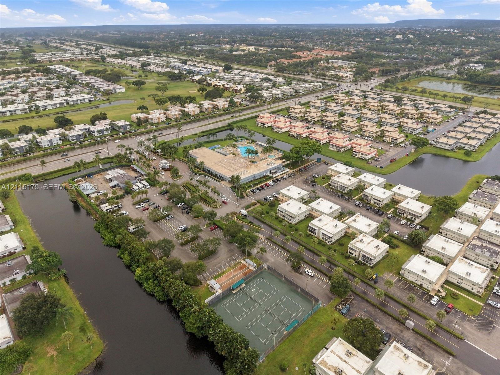 Aerial perspective of one of the satellite clubhouses with an outdoor swimming pool, as well as two clay tennis courts and a sport court