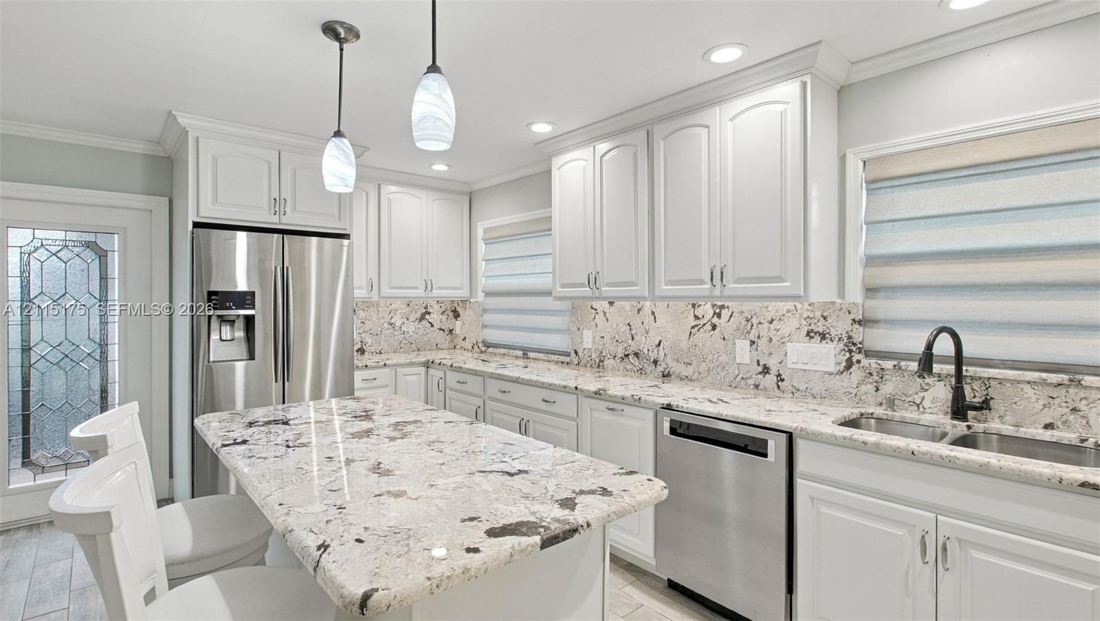 Kitchen featuring white cabinetry, quartz countertops, stainless steel appliances and a central island