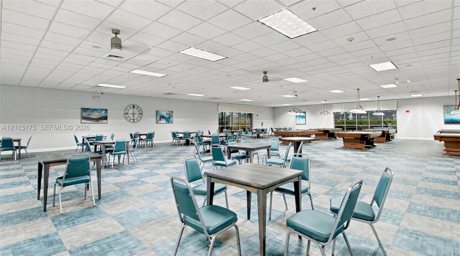 Expansive open-concept recreation room in one of the satellite clubhouses featuring multiple card tables and billiard tables, a drop ceiling with recessed lighting and integrated ceiling fans