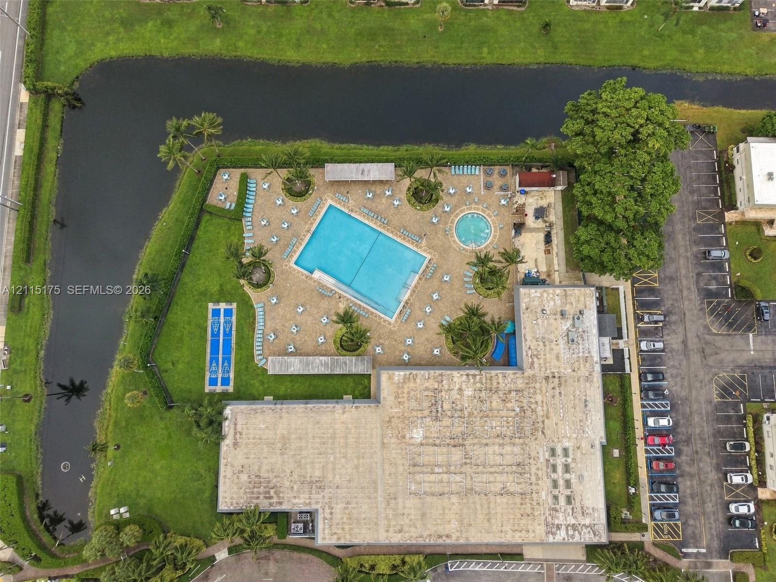 Aerial perspective of one of the satellite clubhouses with amenities including a swimming pool, hot tub, shuffleboard and paved sun deck