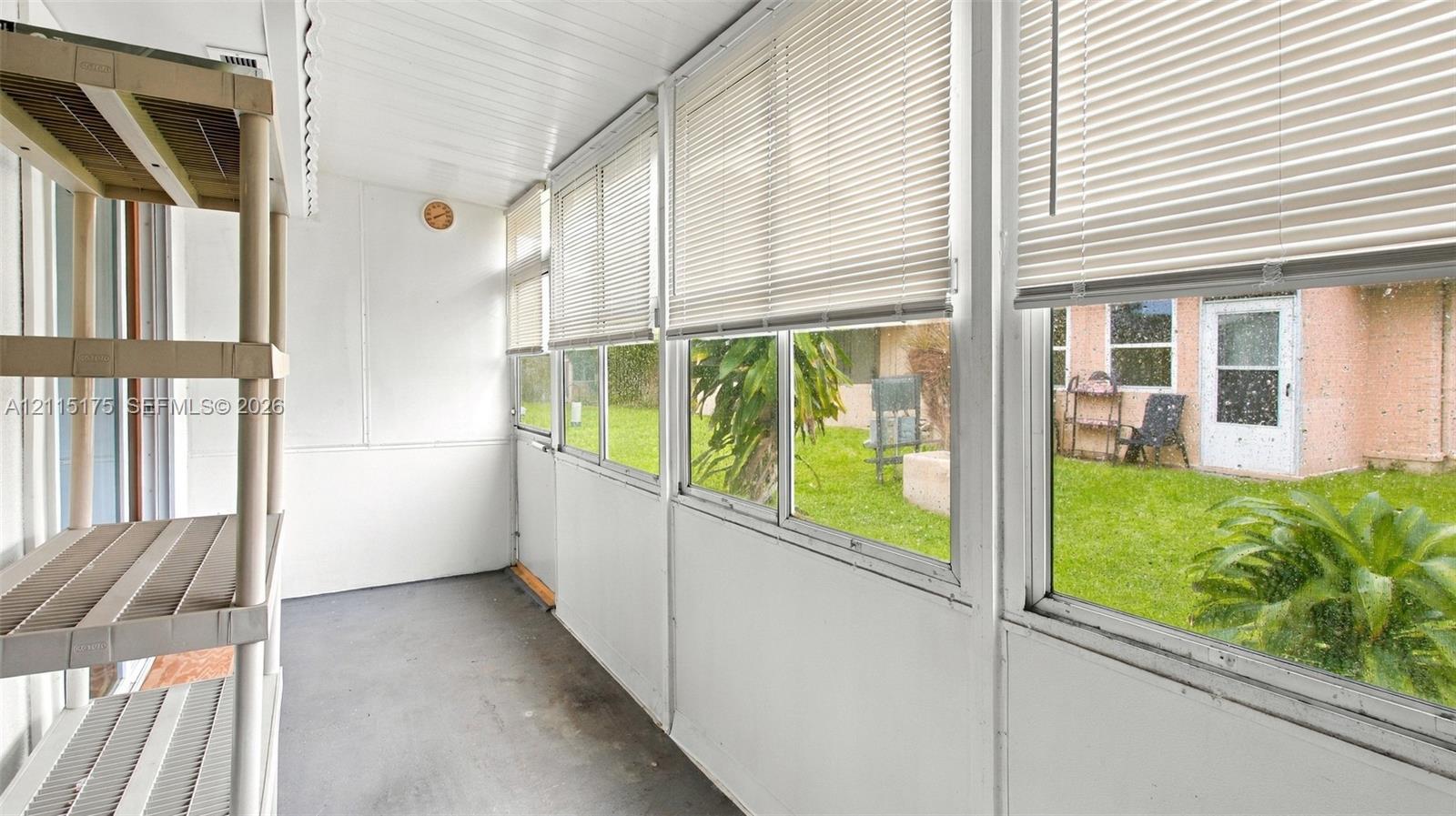 Enclosed lanai featuring expansive windows with horizontal blinds and neutral flooring